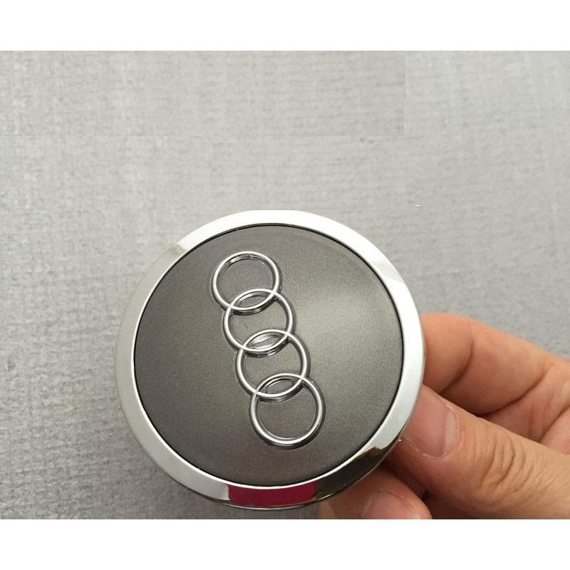 Audi ratlankių dangteliai 69mm pilkos spalvos kaip originalūs laikomas rankose